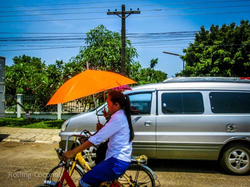 Laotian girl using Sun Umbrella on Bicycle in Vang Vieng Laos Rolling Coconut Ooaworld Photo Ooaworld