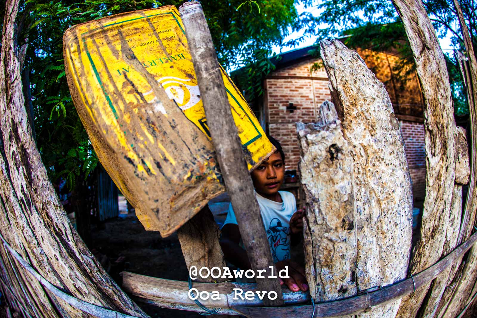 Bagan People Part II Bagan child behind rustic fence with yellow container Photo OOAworld