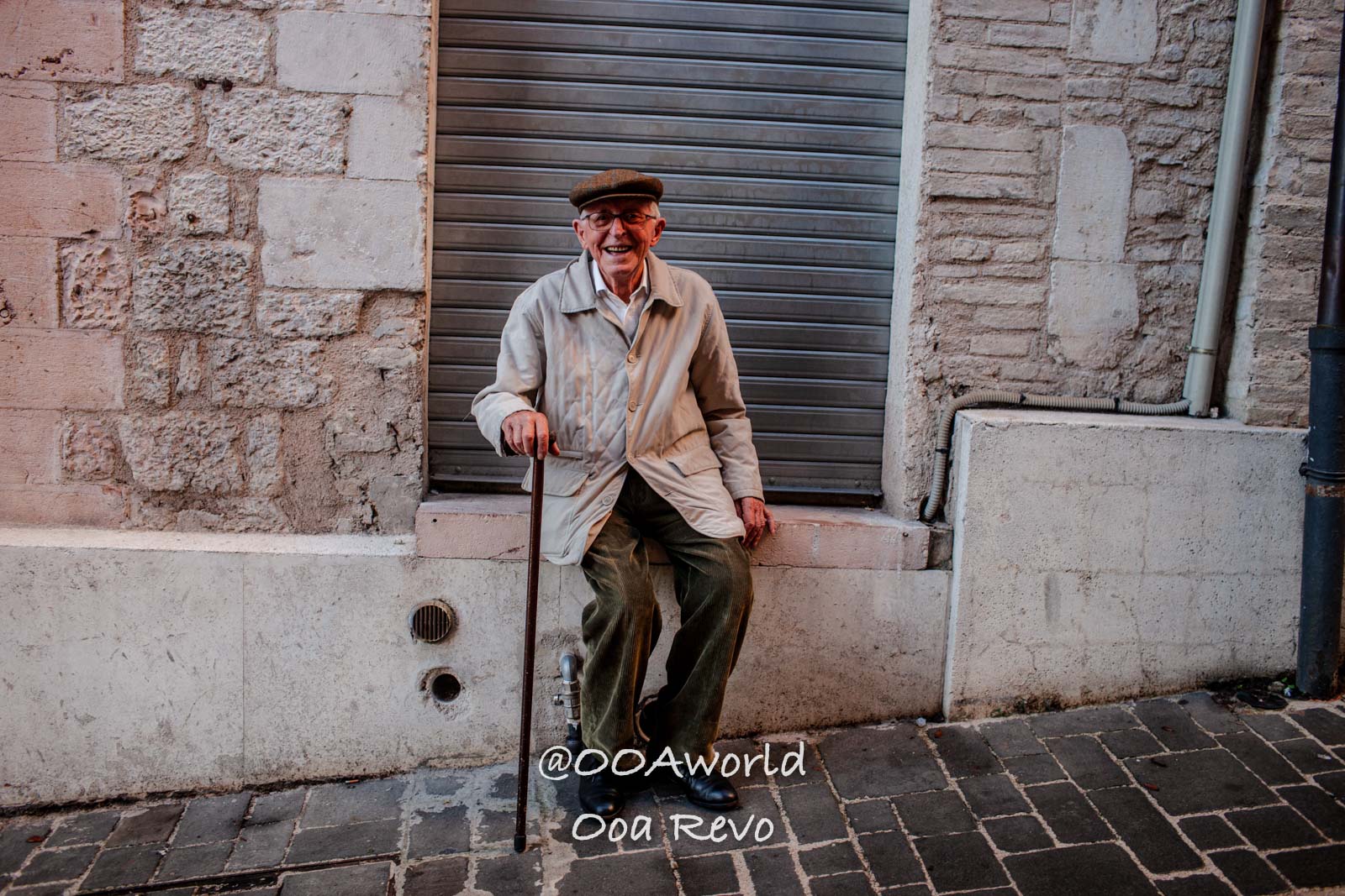 Assissi Italy elderly man sitting with cane on urban street Photo OOAworld