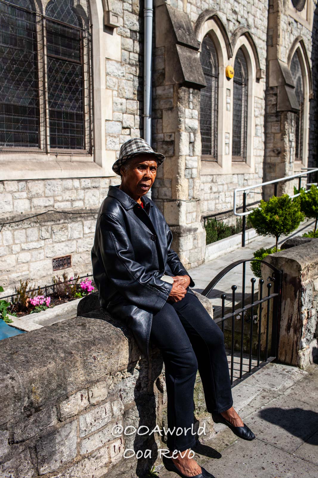 Camden Town London woman sitting by stone church wall wearing leather coat Photo OOAworld