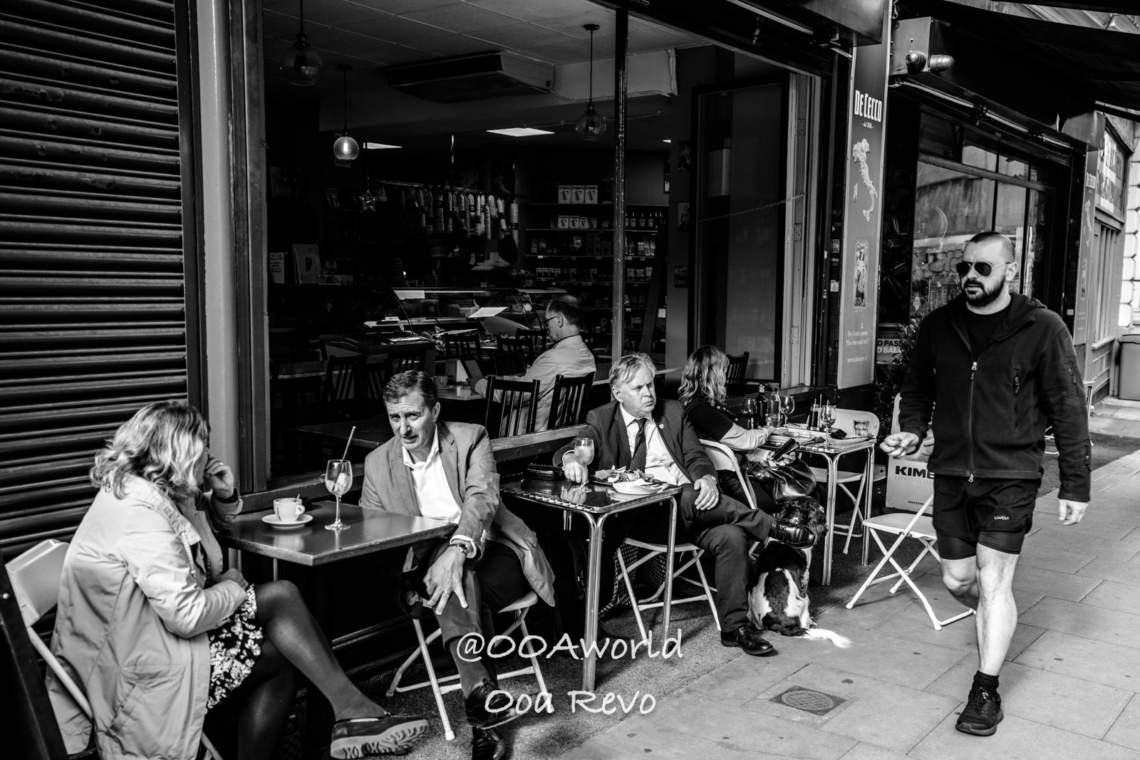 Clerkenwell London people sitting at outdoor cafe with man walking by black and white Photo OOAworld