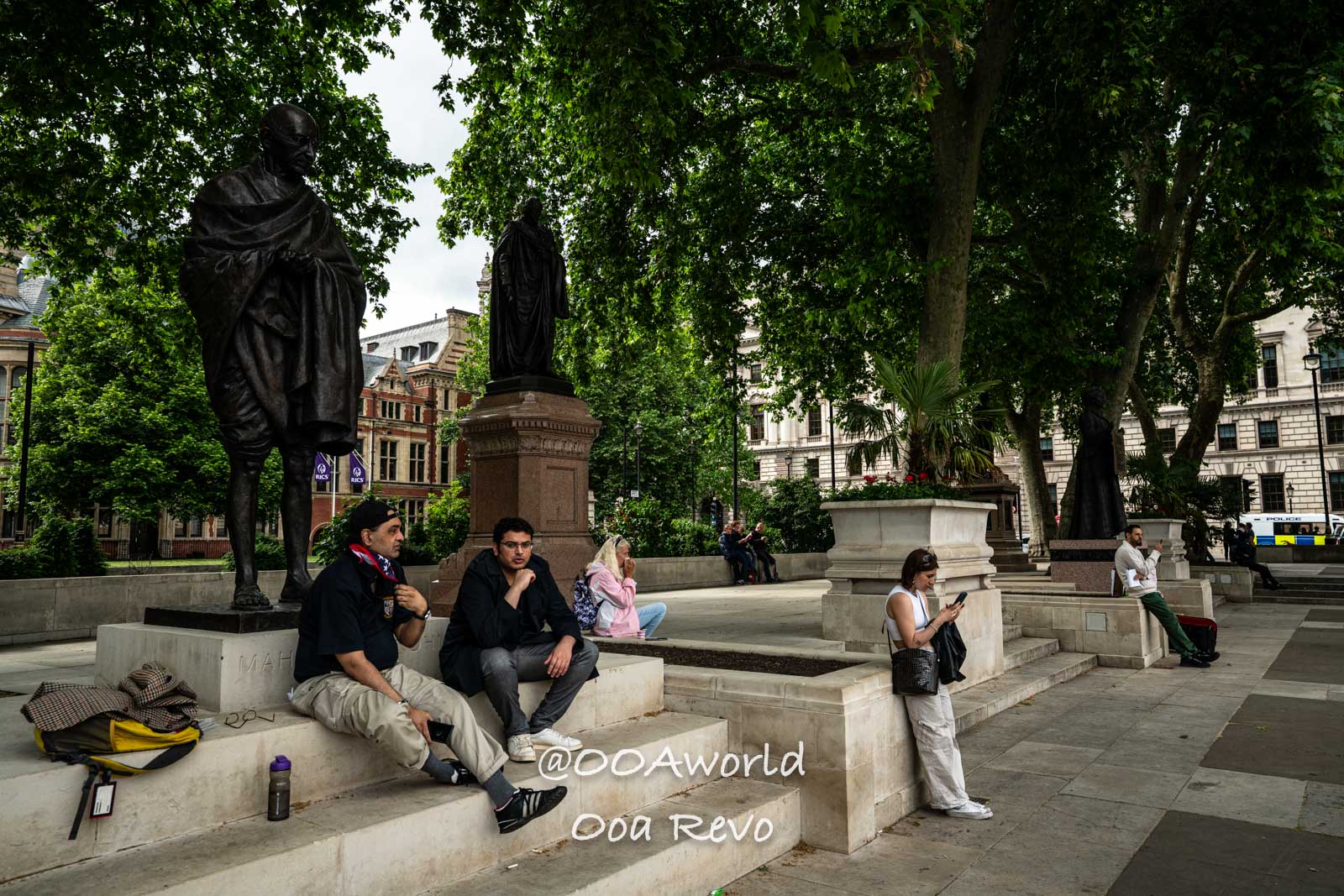 Gandhi statue London park people sitting Photo OOAworld
