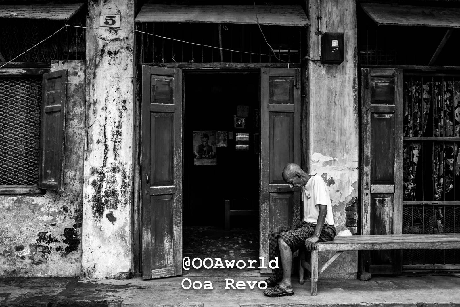 Mandalay People Mandalay Black and white photo of an elderly man sitting on a bench outside a weathered building Photo OOAworld