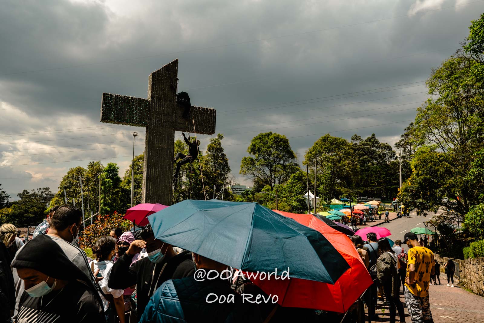 Monserrate Sanctuary Bogota Crowd and Umbrellas by Large Cross Photo OOAworld Monserrate Sanctuary Bogota Crowd with umbrellas near large cross under cloudy skies Photo OOAworld