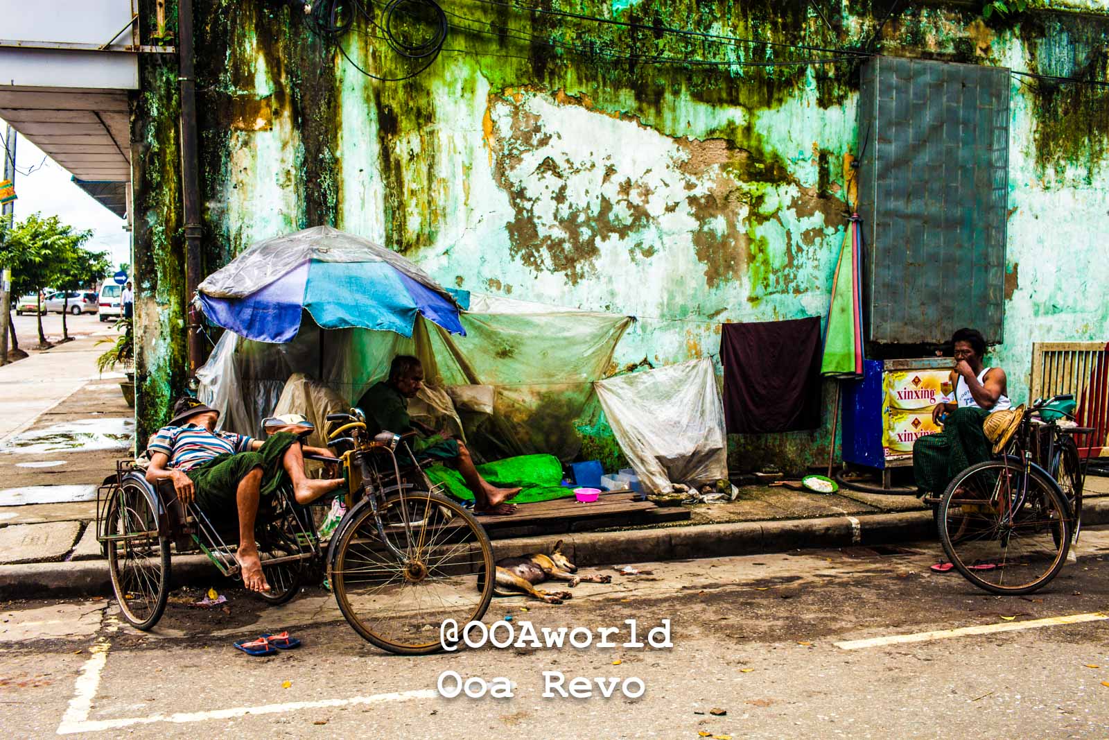 Yangon People and Streets Yangon Street scene with rickshaws and people resting beside a weathered wall Photo OOAworld