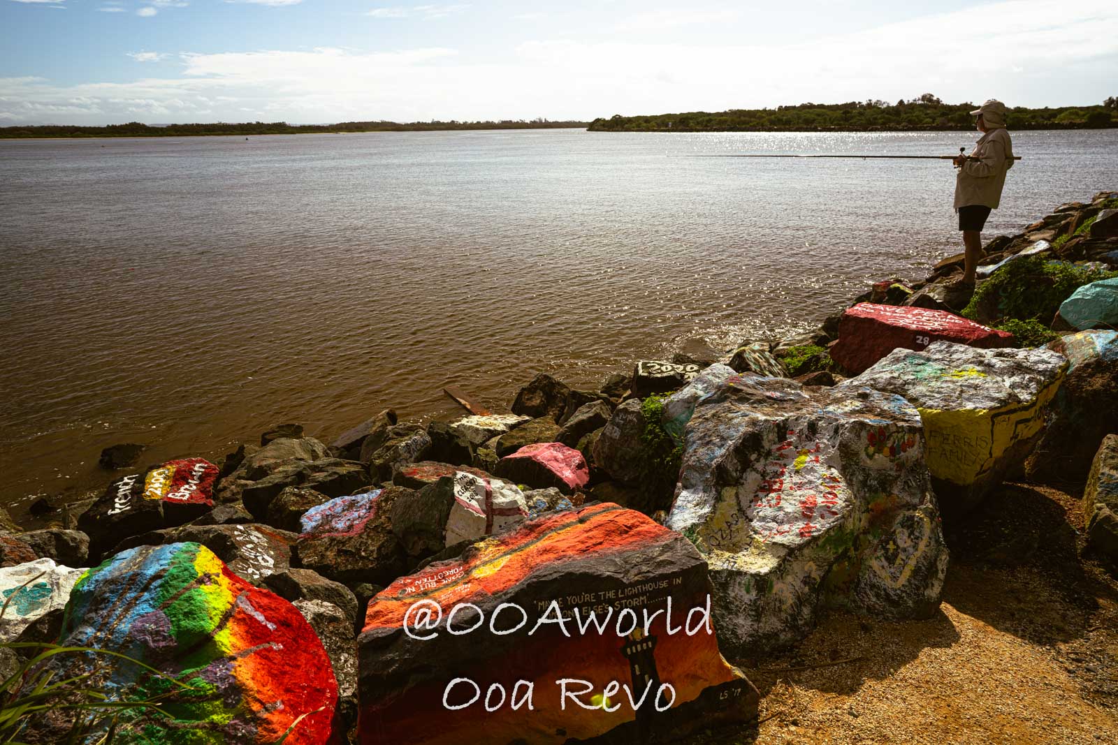 Byron Bay, Port Macquarie Australia man fishing by painted rocks at lake Photo OOAworld