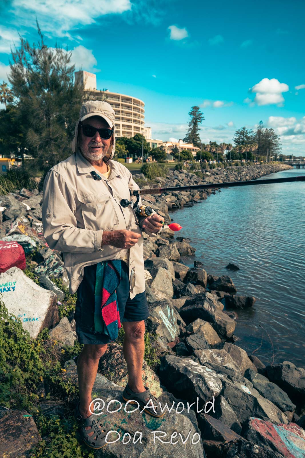 Byron Bay, Port Macquarie Australia man fishing by riverbank with buildings in background Photo OOAworld