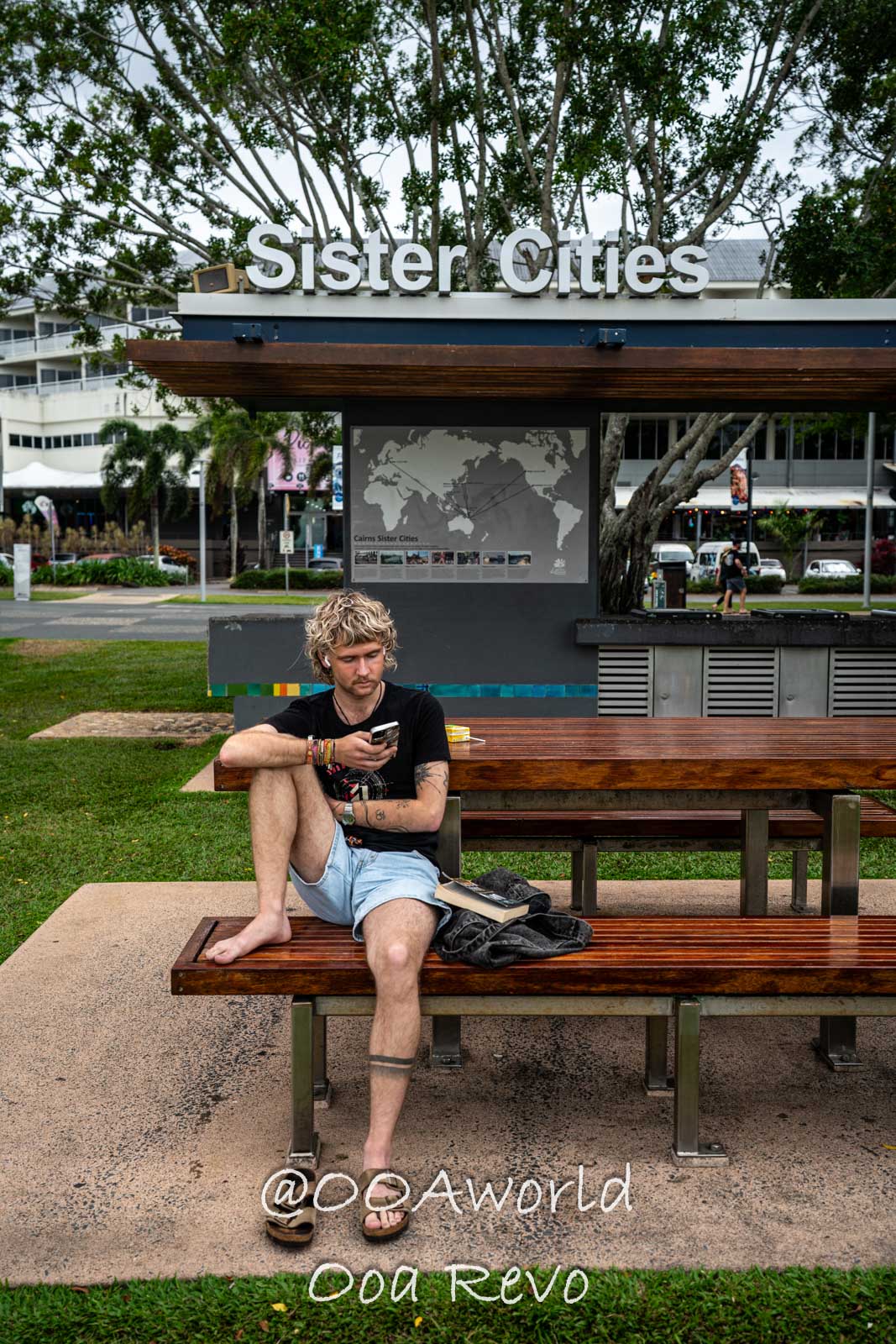 Cairns Australia Man sitting at Cairns Sister Cities sign Photo OOAworld