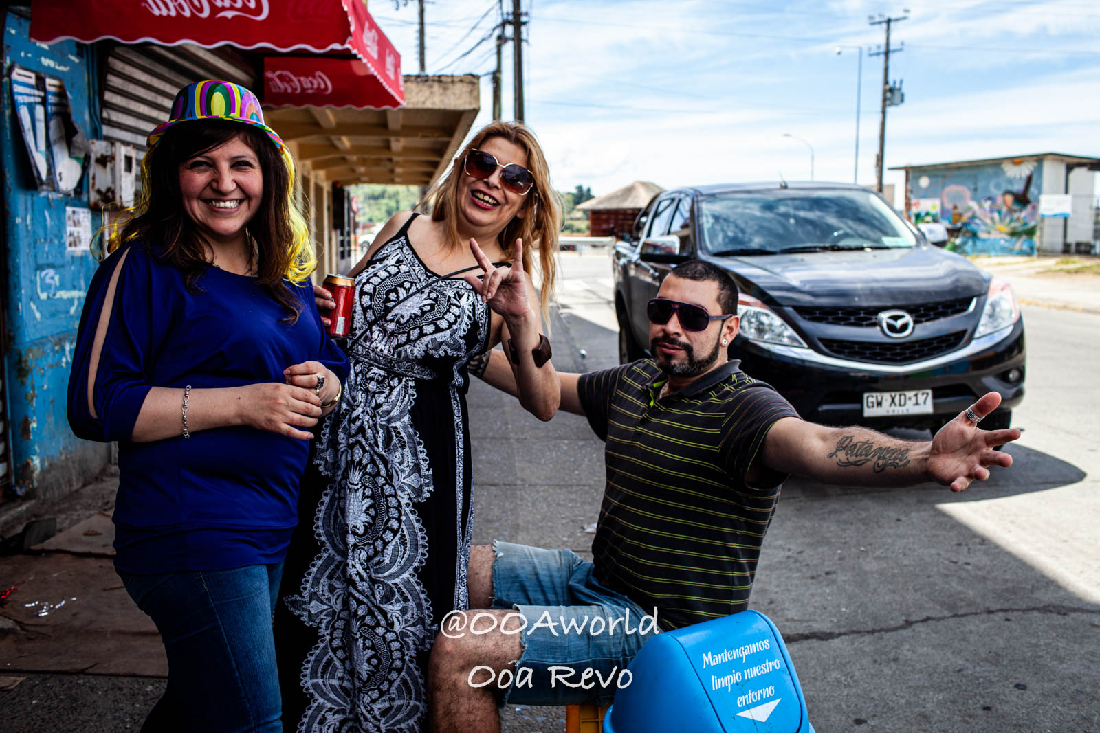 Palafitos and NYE Chiloe Group of friends smiling on a street with car and CocaCola umbrellas Photo OOAworld