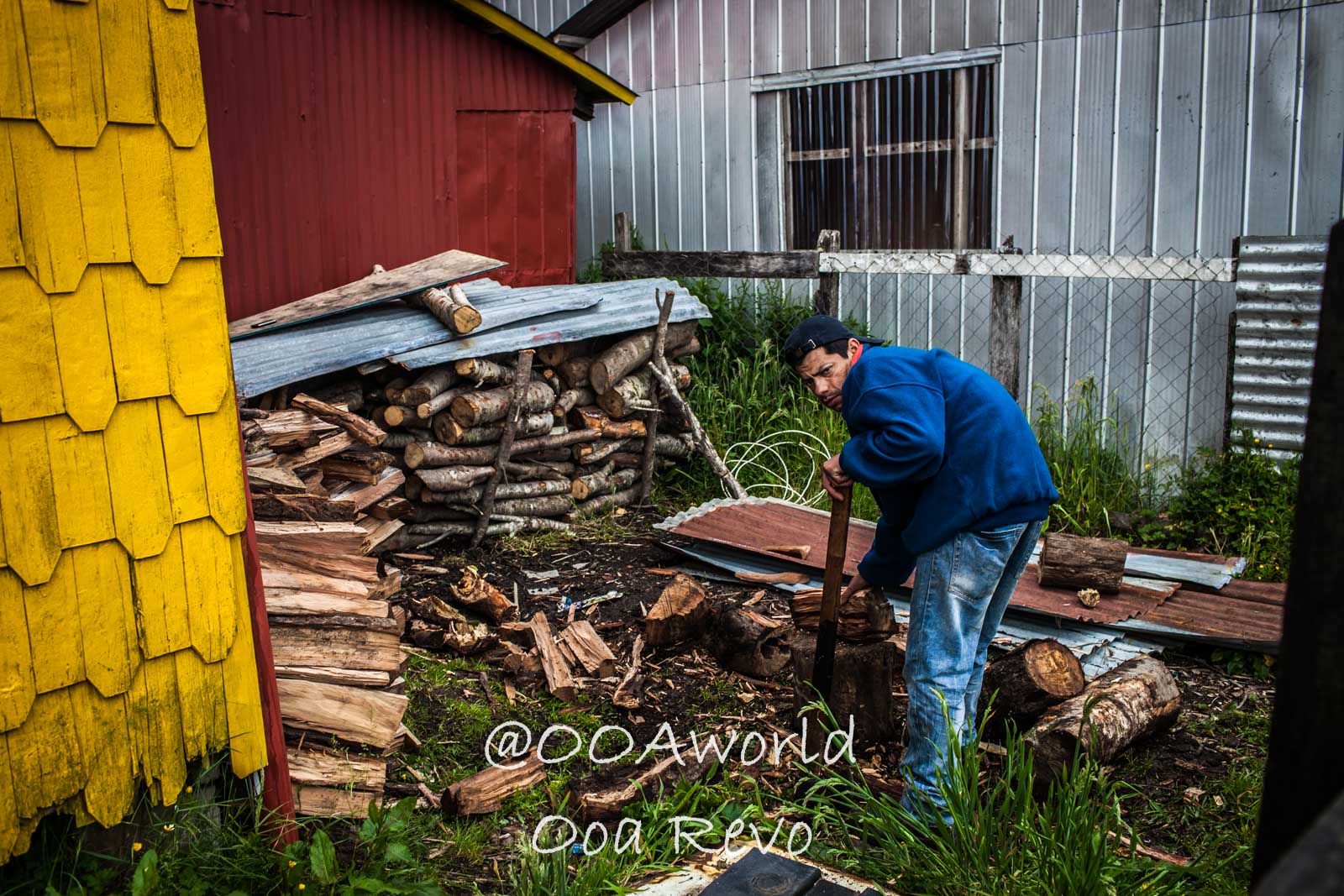 People Portraits Streets Puerto Cisnes Man chopping wood in rural setting Photo OOAworld